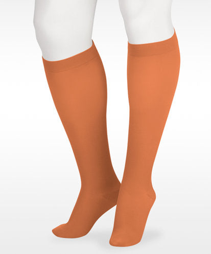 A display showcasing the Juzo Soft Closed Toe Knee High with Silicone Band in the Color Cinnamon