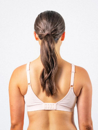 Woman facing away from the camera, wearing the Prairie Wear Hugger Aria compression bra in the color Wild Rose