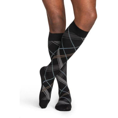 Male wearing his Sigvaris Microfiber Pattern 20-30 mmHg compression knee high in the design black plaid.