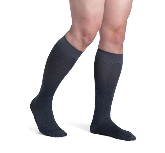 Male wearing his Sigvaris Microfiber Pattern 20-30 mmHg compression knee high in the design graphite chevron.