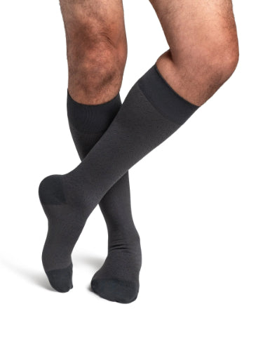 A male wearing his Sigvaris Microfiber Pattern 20-30 mmHg compression knee-high stocking with a graphite confetti design.