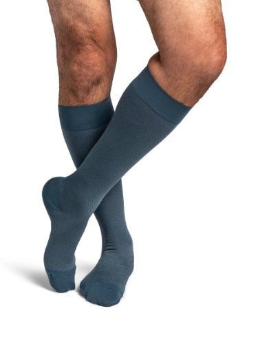 A male wearing his Sigvaris Microfiber Pattern 20-30 mmHg compression knee-high stocking with a storm blue confetti design.