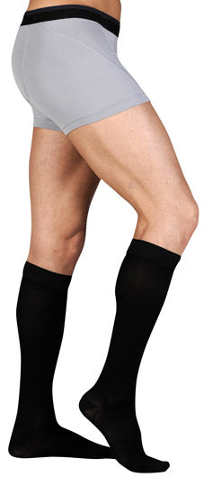 Guy wearing his Juzo Dynamic Closed Toe Knee High 20-30 mmHg Compression Stockings with 5 cm Silicone Dot Band in the color Black