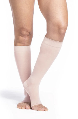 Female leg wearing Sigvaris 782C Sheer Open Toe Knee High Compression Stockings in the color Warm Sand