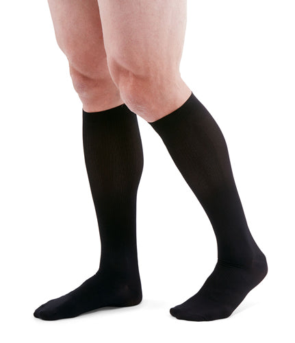 man wearing a pair of black knee-high compression socks the Mediven for Men Classic sock has a thin verticle pinstripe design