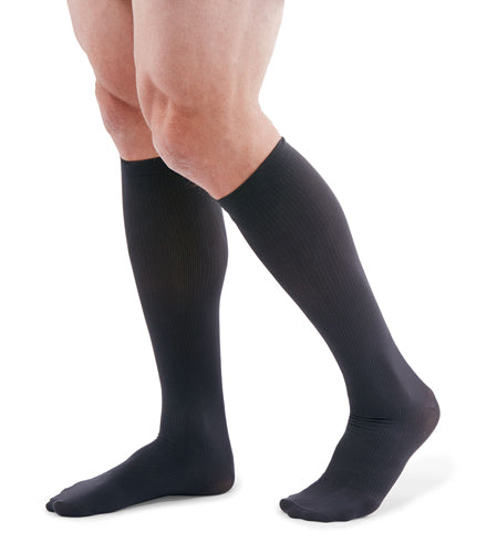 man wearing a pair of grey knee-high compression socks the Mediven for Men Classic sock has a thin verticle pinstripe design